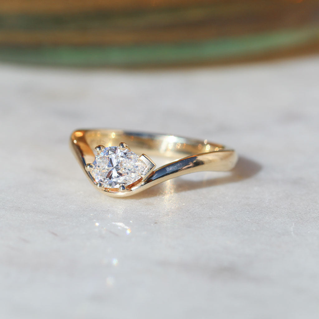 Flow engagement ring. pear cut diamond with a curved band