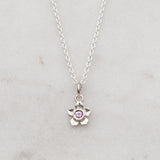 Silver forget me not flower necklace with a pink sapphire