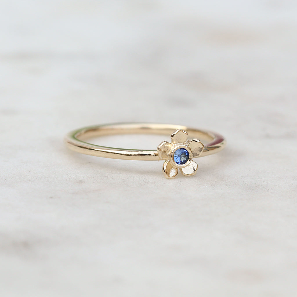 Gold forget me not flower ring with a blue sapphire