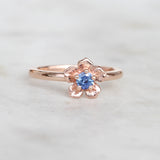 Rose gold forget me not flower ring with a blue sapphire