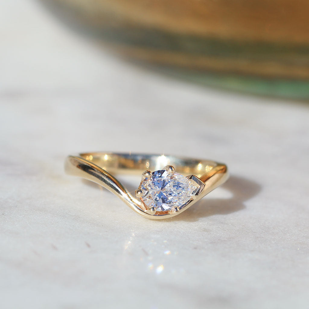 Flow engagement ring. Pear cut diamond with a curved band