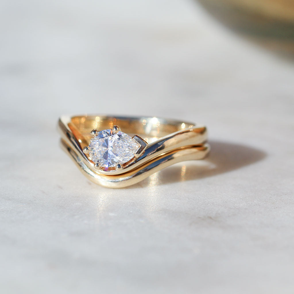 Pear cut diamond engagement ring with a curved band. Matching fitted wedding ring