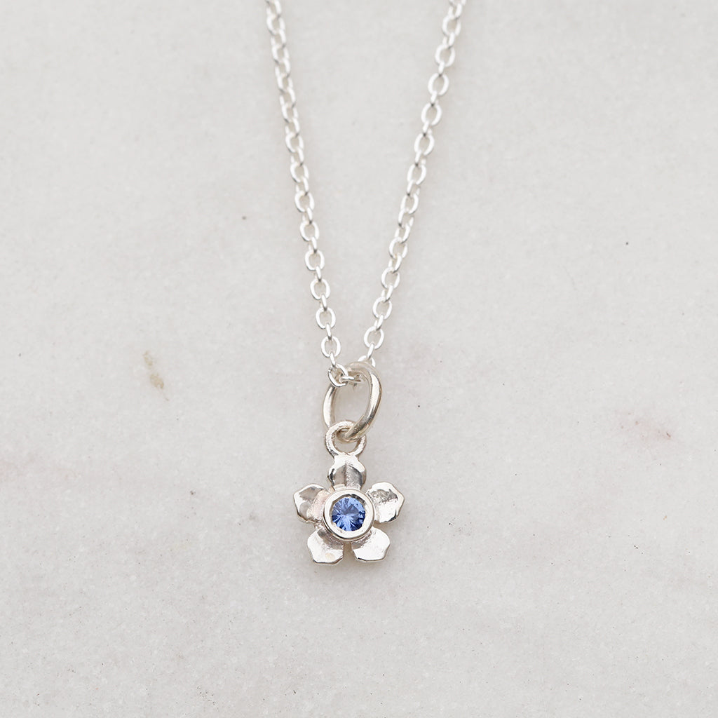 Silver forget me not flower necklace with a blue sapphire