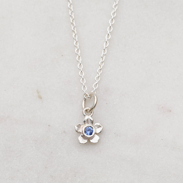Silver forget me not flower necklace with a blue sapphire