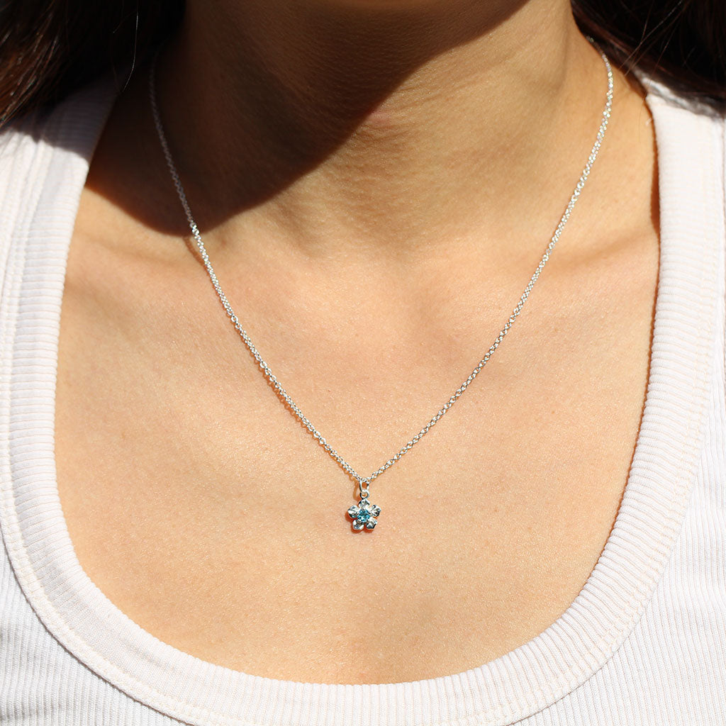 Forget me not flower necklace in silver set with a blue topaz