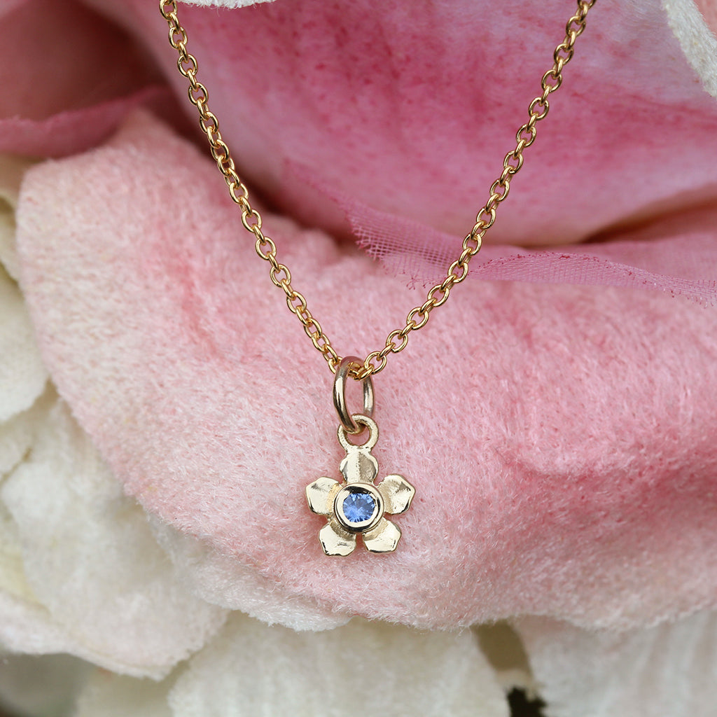 Gold forget me not flower necklace with a Ceylon blue sapphire