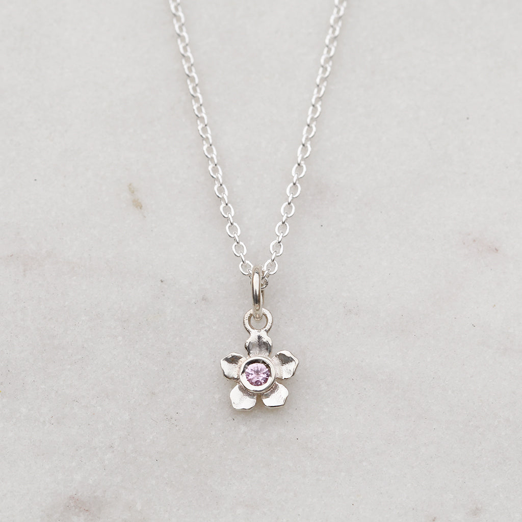 Silver forget me not flower necklace with a pink sapphire