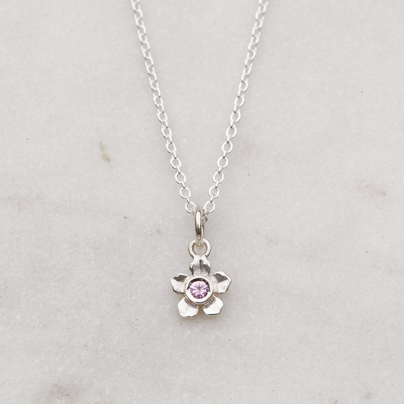 Silver forget me not flower necklace with a pink sapphire