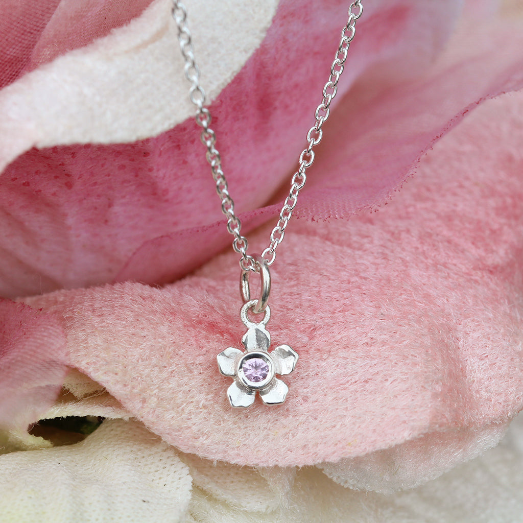 Silver forget me not flower necklace with a pink sapphire