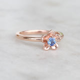 Rose gold forget me not flower engagement ring with a blue sapphire