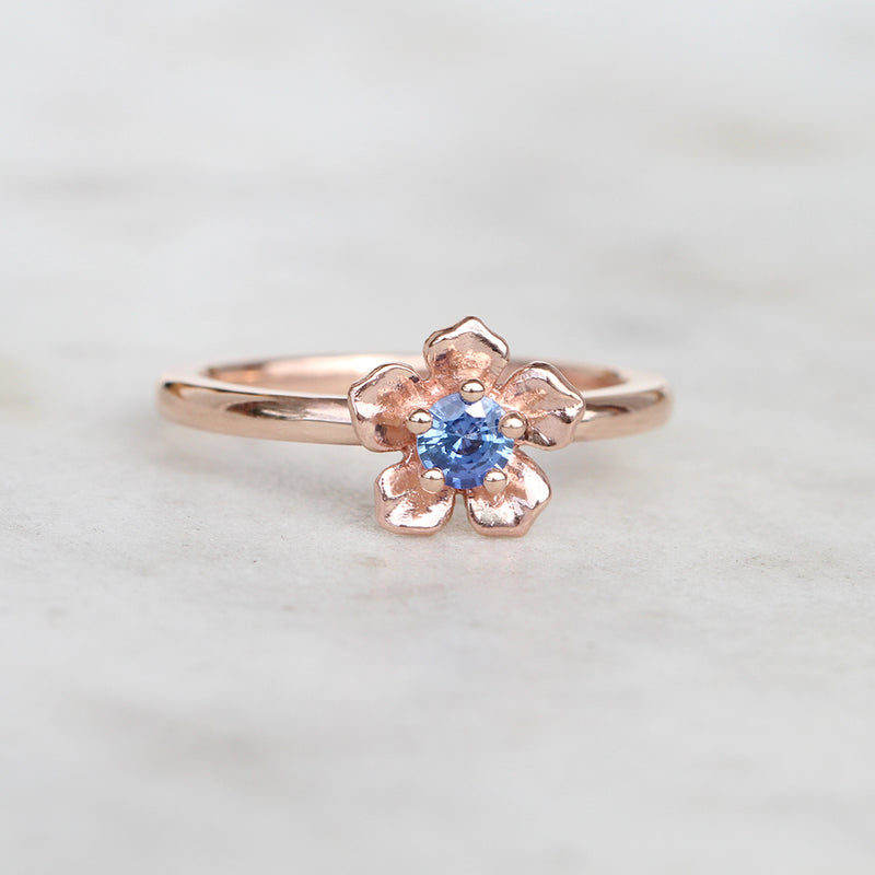 Rose gold forget me not flower ring with a blue sapphire