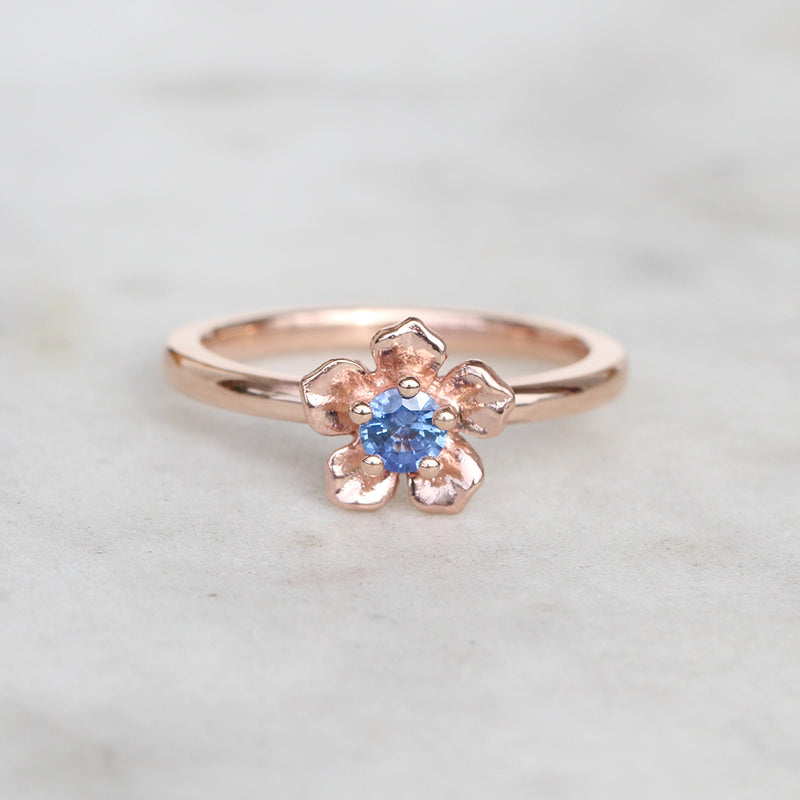 Rose gold forget me not flower ring with a sapphire