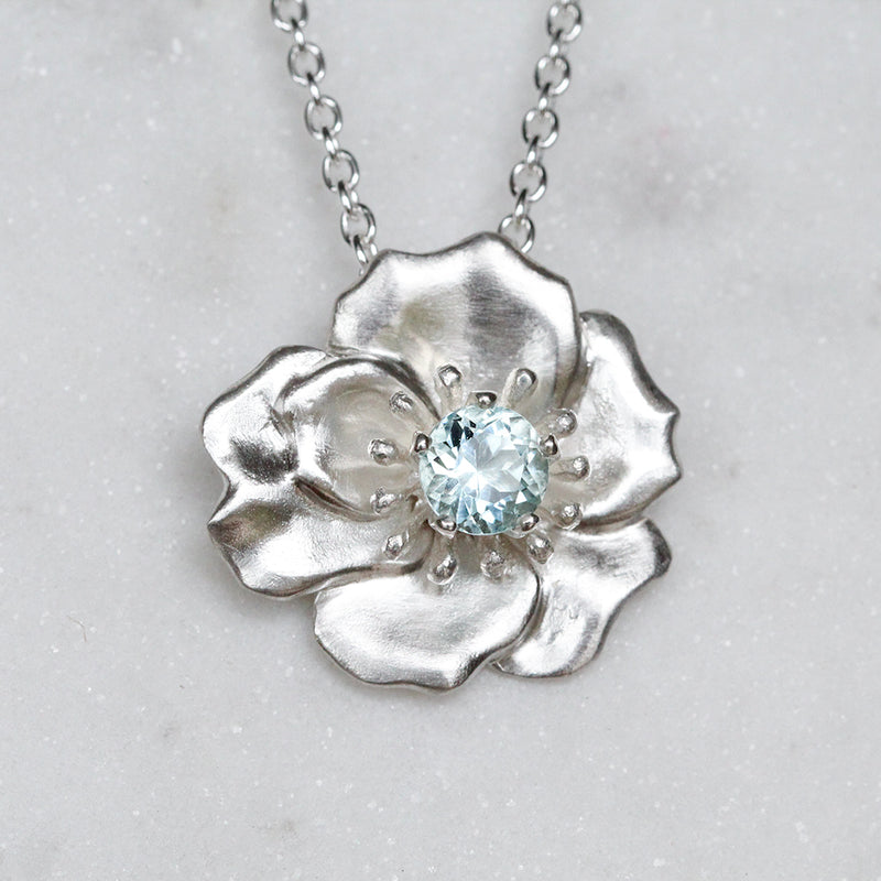 Eva rose necklace in silver set with a blue aquamarine gemstone